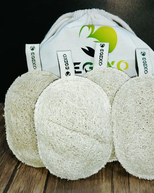 Four loofah pads with woven EGEXO tags standing in front of an EGEXO printed bag
